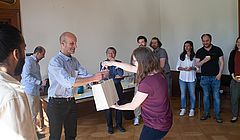 Die Mitarbeitenden des Europainstituts überreichen Corey Ross ein Begrüssungsgeschenk